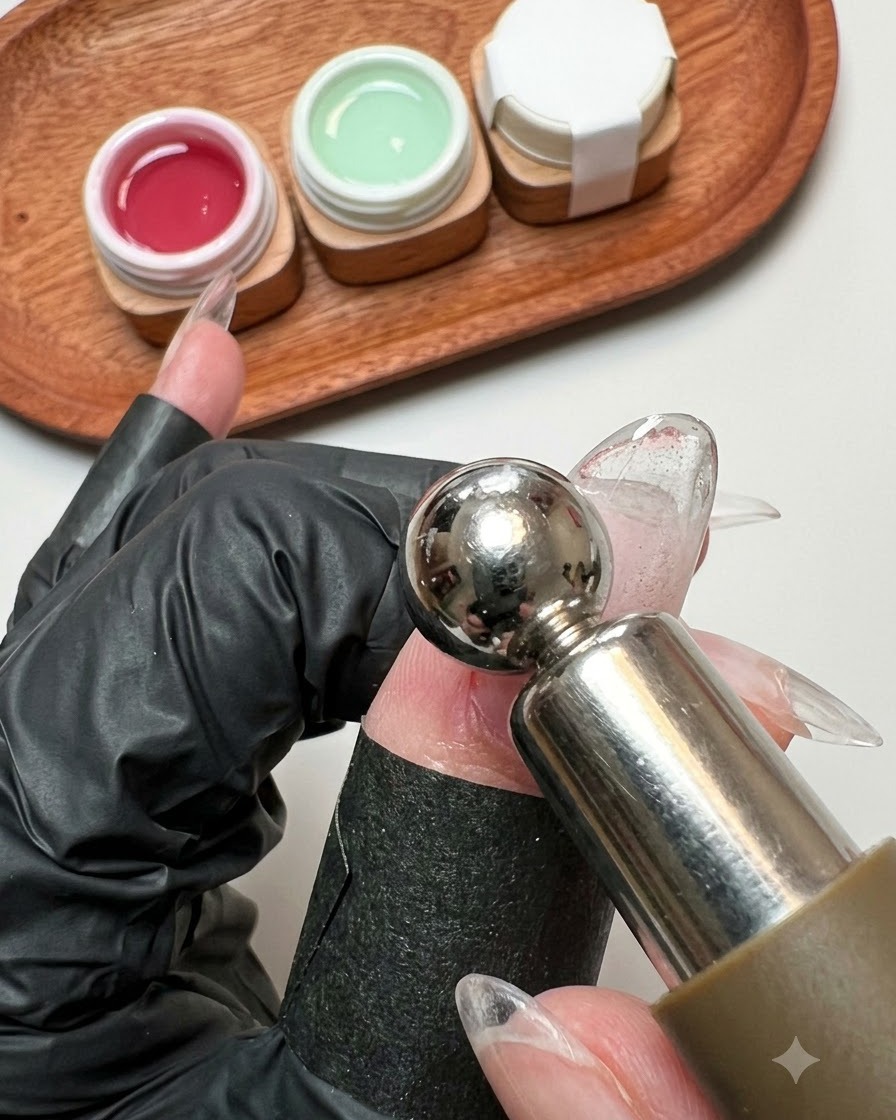 A magnetic wand tool hovering closely over a wet glitter gel nail surface.