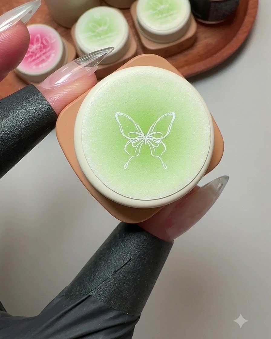 A solid gel container featuring a butterfly illustration on the lid, surrounded by green and pink gel pots.