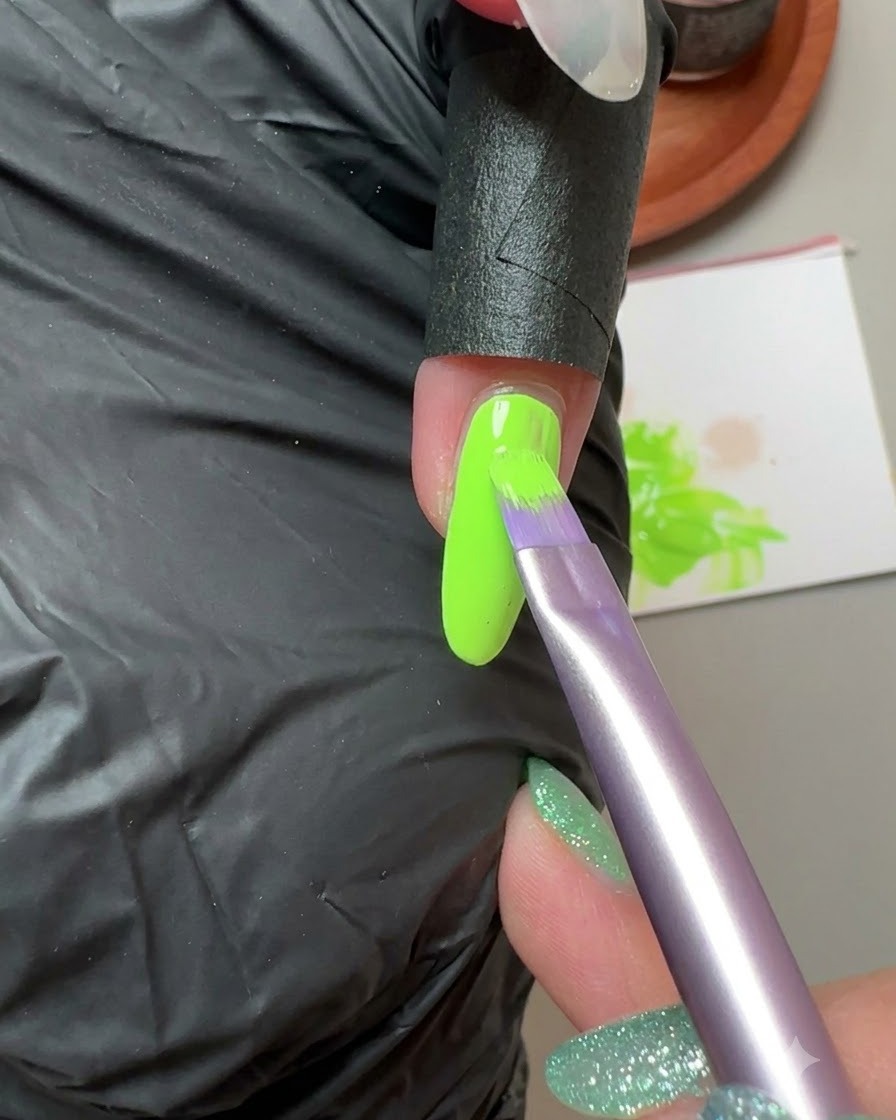 A brush applying fluorescent green solid gel onto the small fingernail.