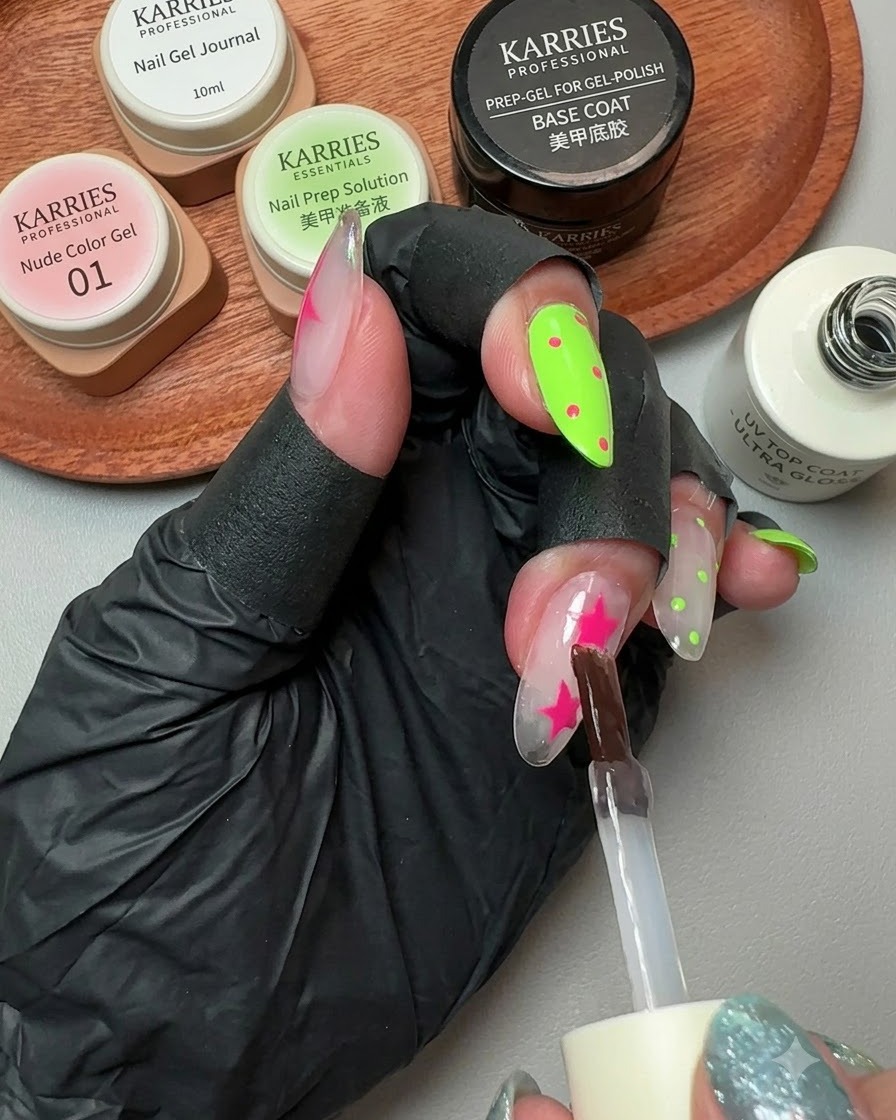 A brush applying glossy top gel over a decorated nail with pink stars and polka dots.