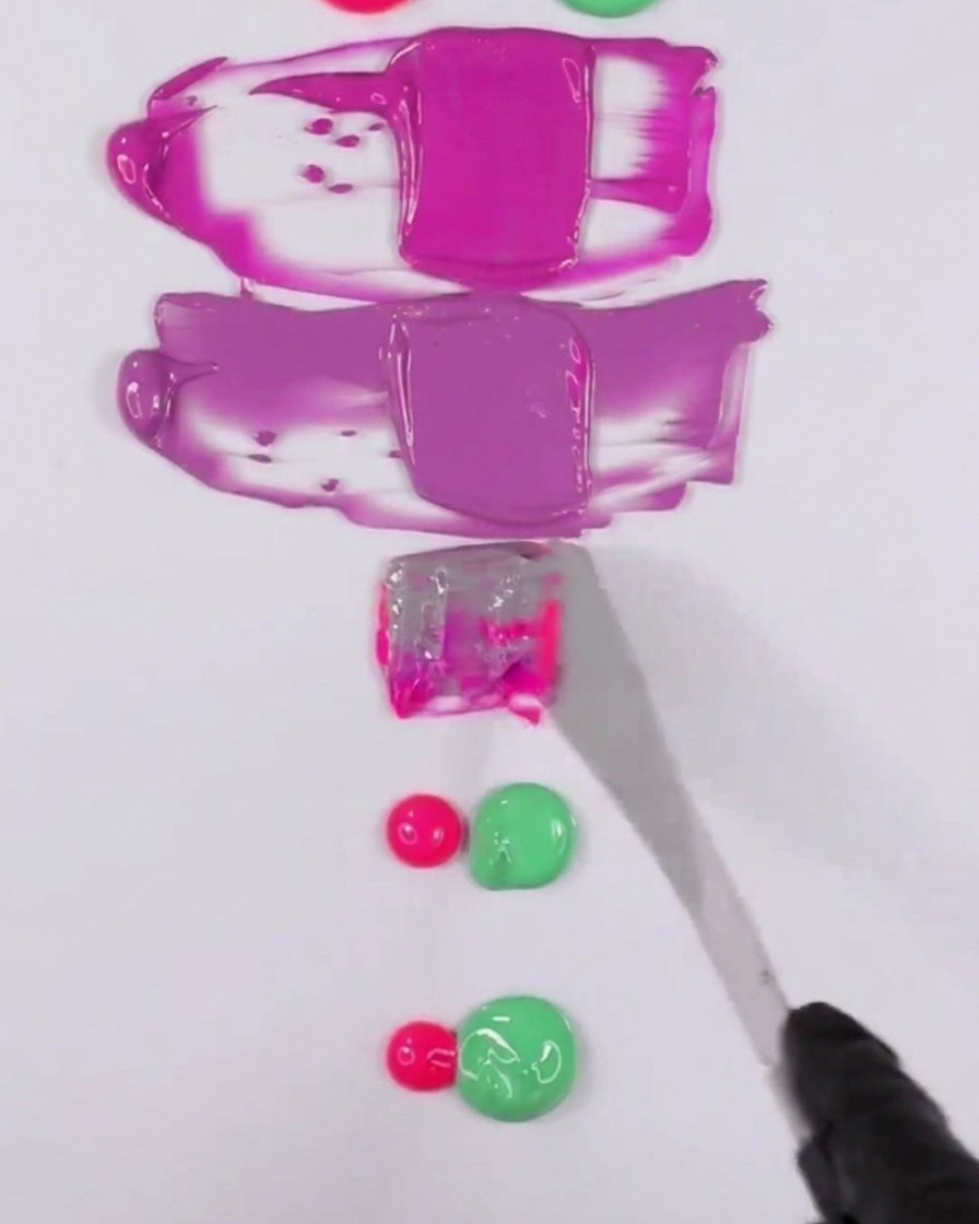 A metal spatula blending a mixture of pink and green gel polish to create a muted purple tone.