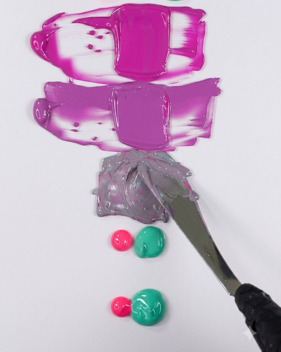 A metal spatula smoothing a muted purple gel mixture into a clean horizontal swatch on a white surface.