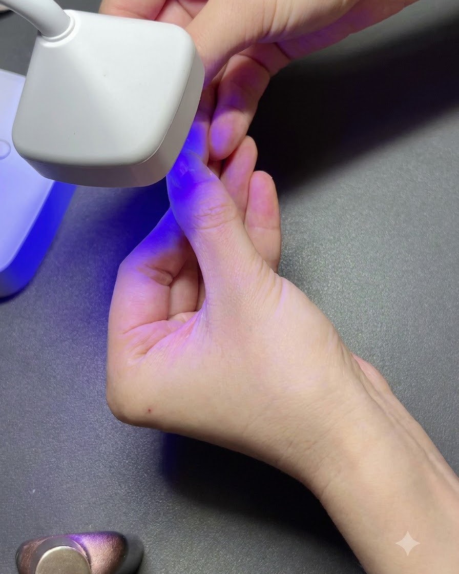 A portable white UV lamp curing a clear gel nail tip on a finger under purple light.