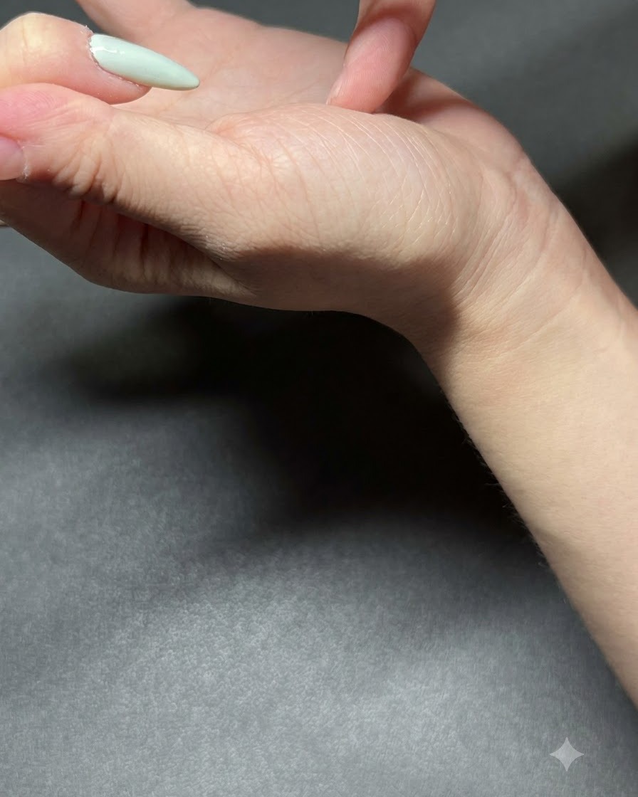 A fine brush applying light mint green gel polish to a fingernail.
