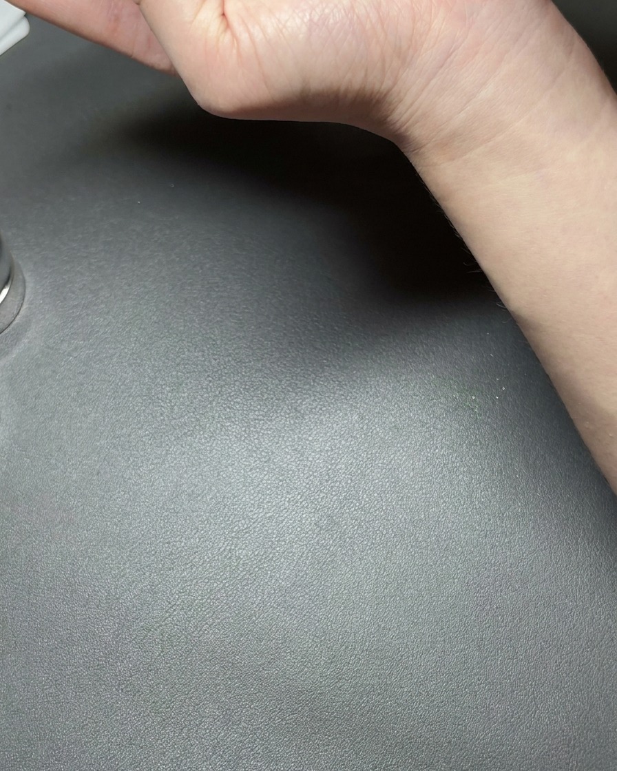 A hand holding a small neodymium magnet close to a nail coated with metallic green cat-eye gel, creating a bright reflective line.