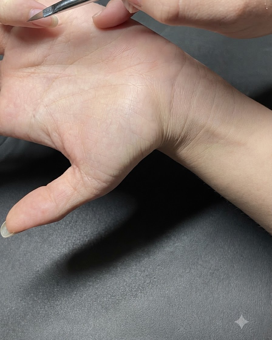 A dotting tool placing small mint green dots onto a manicured fingernail.