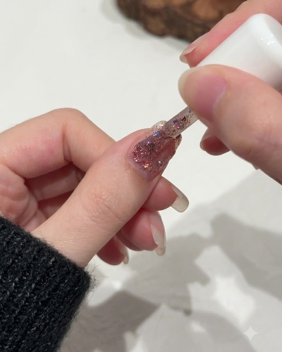A brush delicately refining the glitter distribution near the cuticle line of a fingernail.
