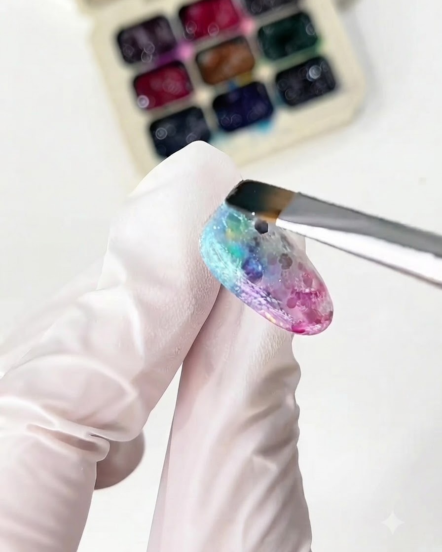 A fine brush applying yellow and green glass gels on the nail.