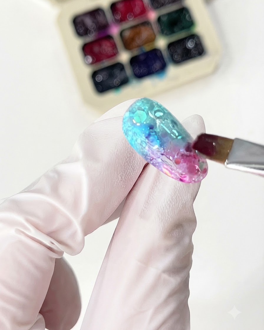 A fine brush applying orange glass gel to complete the gradient design.