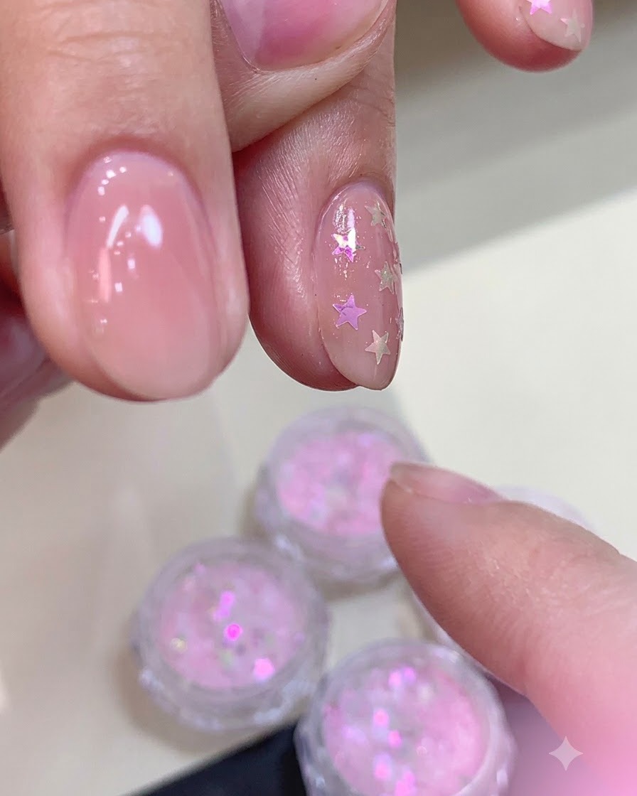 Applying a thick layer of matte top coat over a nail decorated with self-curved star glitter.