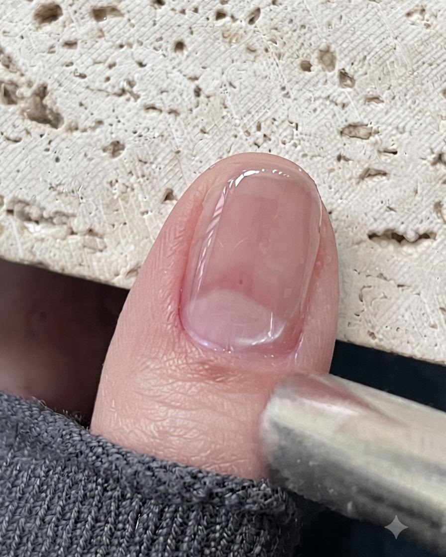 A magnet tool positioned close to a glossy cat eye gel nail to pull the magnetic particles.