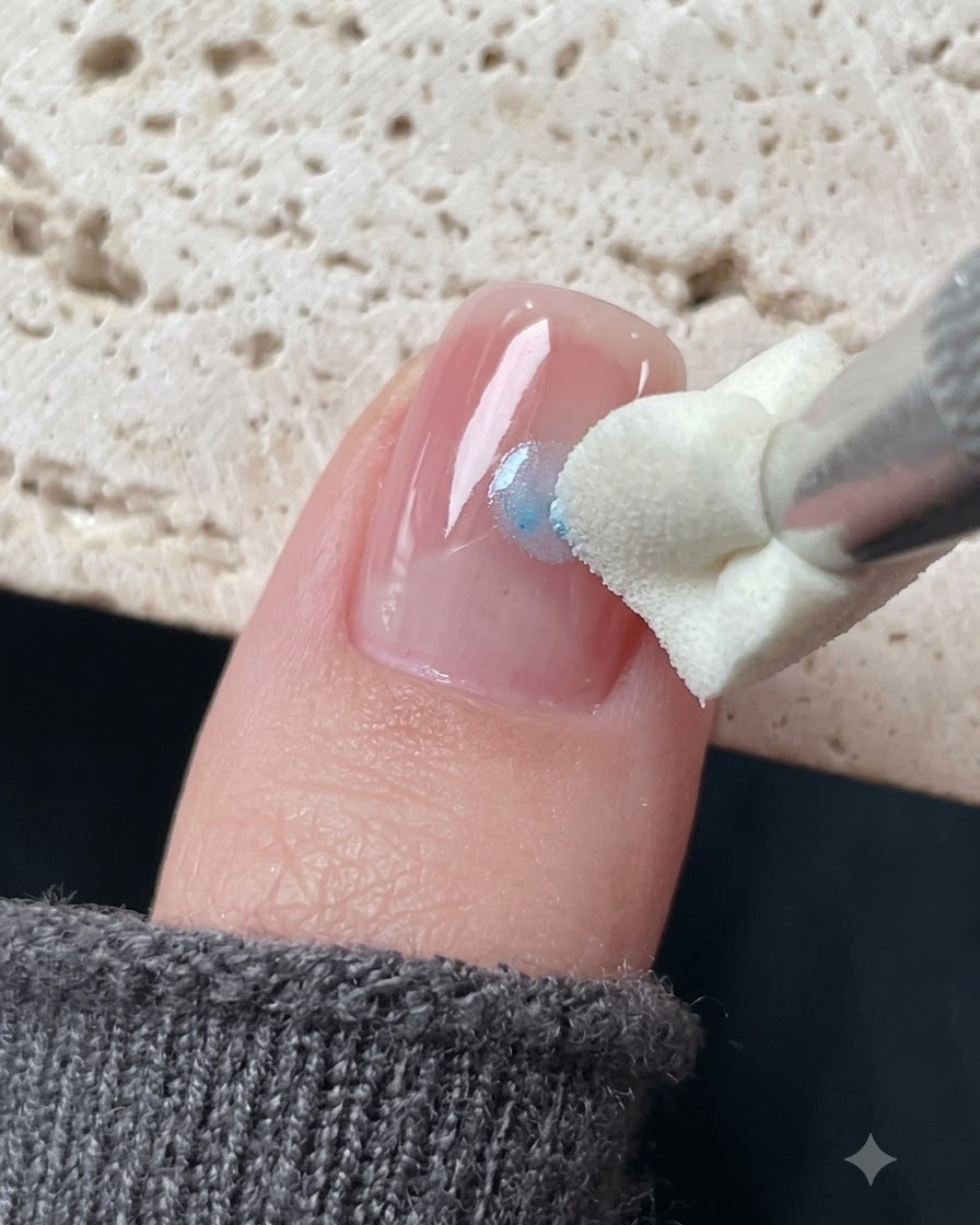 A silicone stamping tool dabbing blue glass gel around a star sticker on a nail.