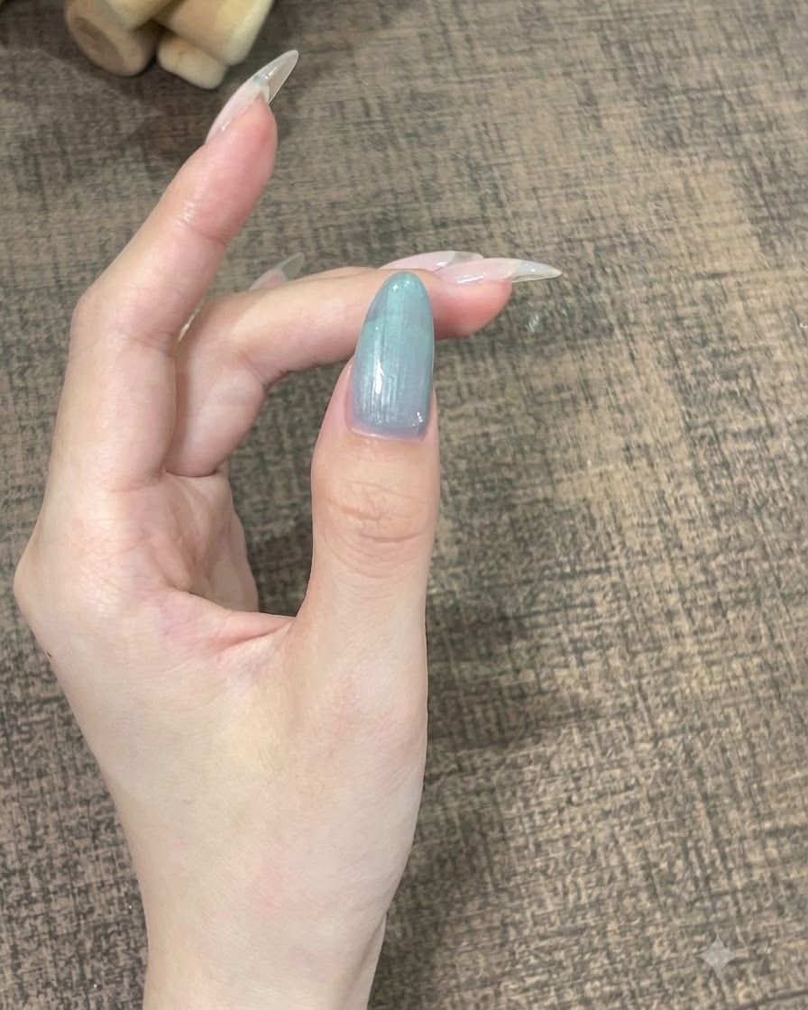 A close-up of a single finger with self-leveling gel being held still to settle into a smooth curve.