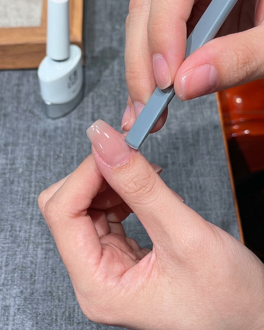 A finger placed under a small UV/LED mini lamp for curing.