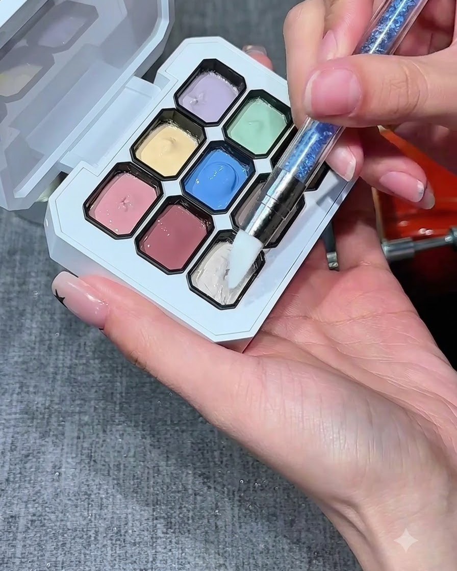A silicone nail brush dipping into a well of milky white gel on a multi-color palette.