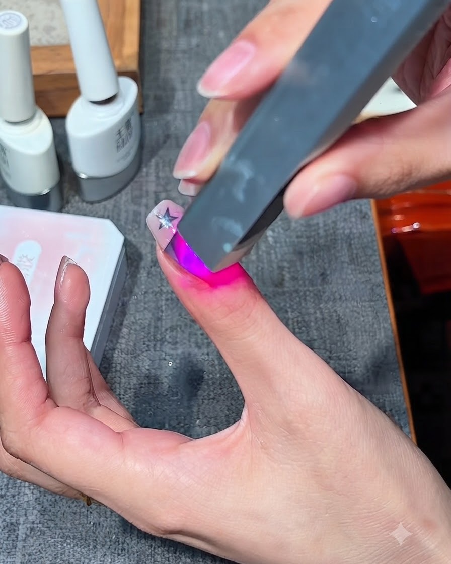 A portable mini UV/LED nail lamp curing a gel design on a finger.