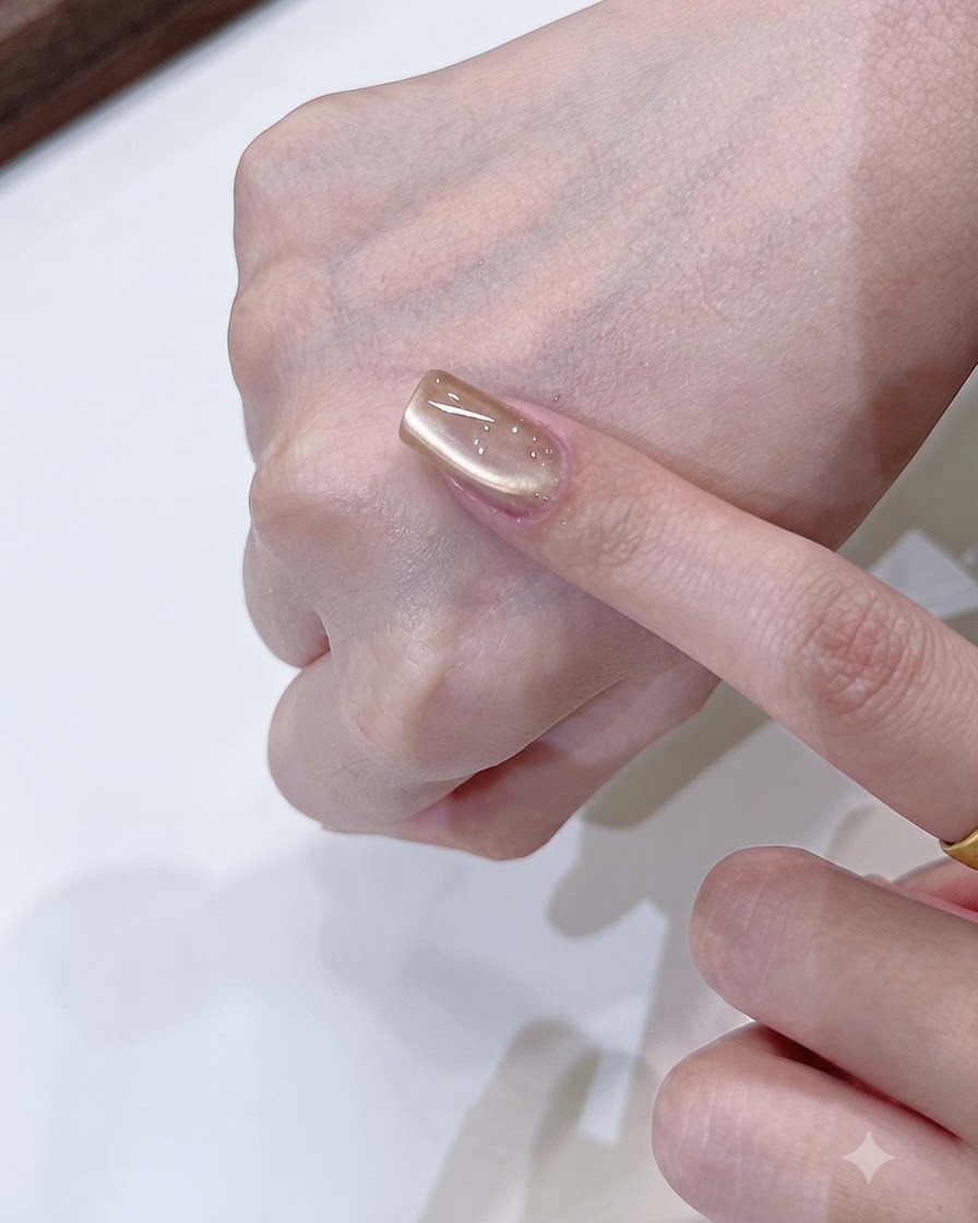 A magnet tool shaping a soft single-side light reflection on a champagne gold cat eye nail.