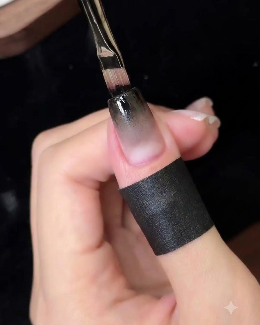 A fine detailing brush applying a concentrated layer of black gel onto the upper nail edge.