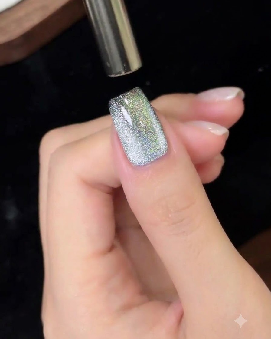 A magnetic tool being moved from top to bottom over a cat eye gel nail.