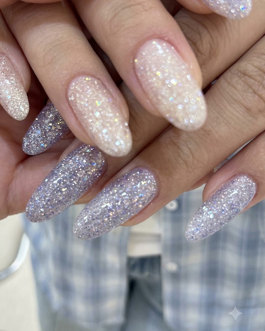 A close-up shot of hands with interlocked fingers displaying glossy pinkish nude and purple glitter gel nails.