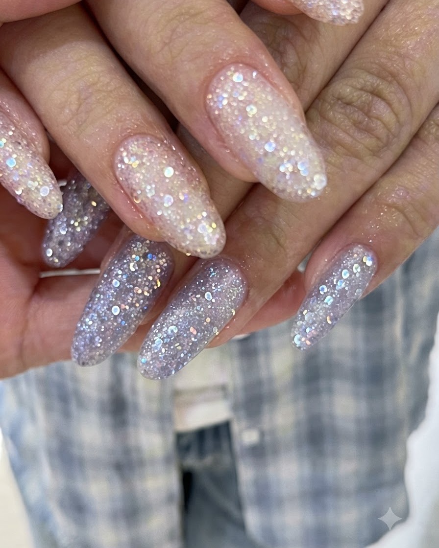 Fingers overlapping to display long extensions coated in pink and purple shimmering glitter gel.