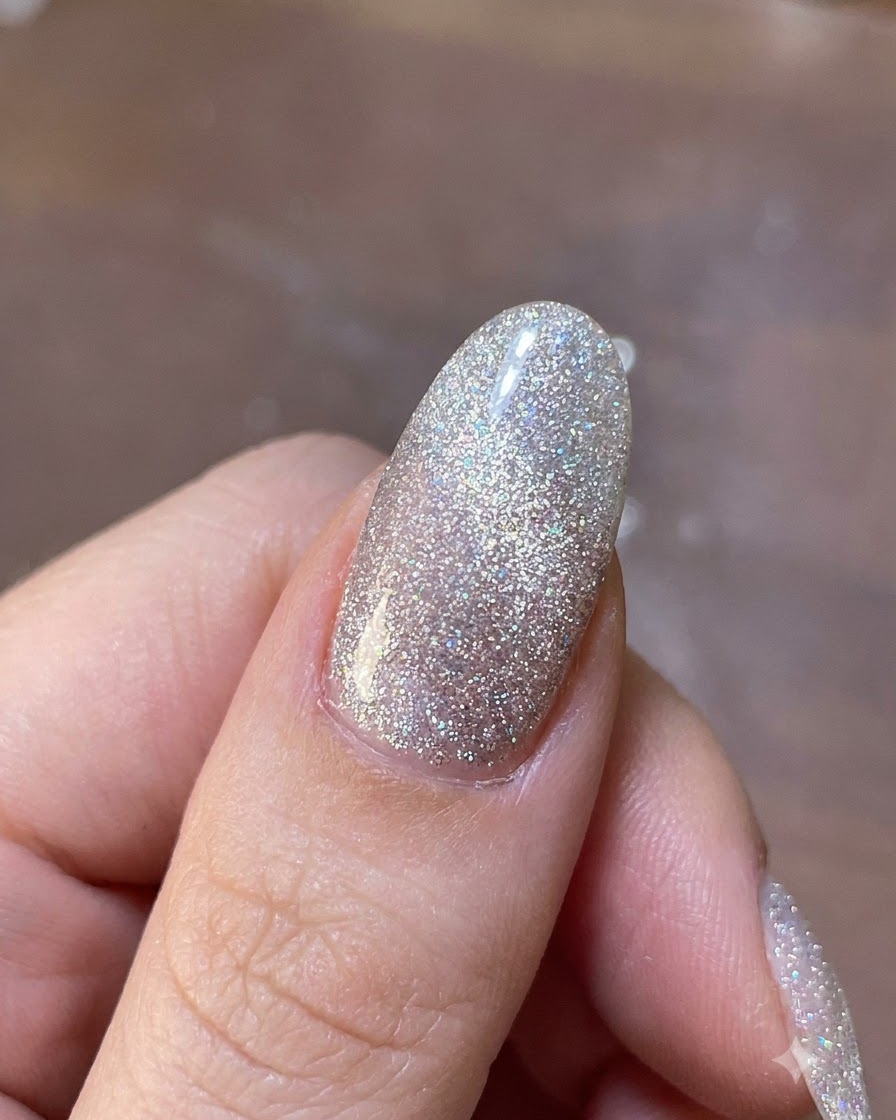 A magnet tool hovering above a shimmering gel nail to shift the magnetic glitter particles into place.
