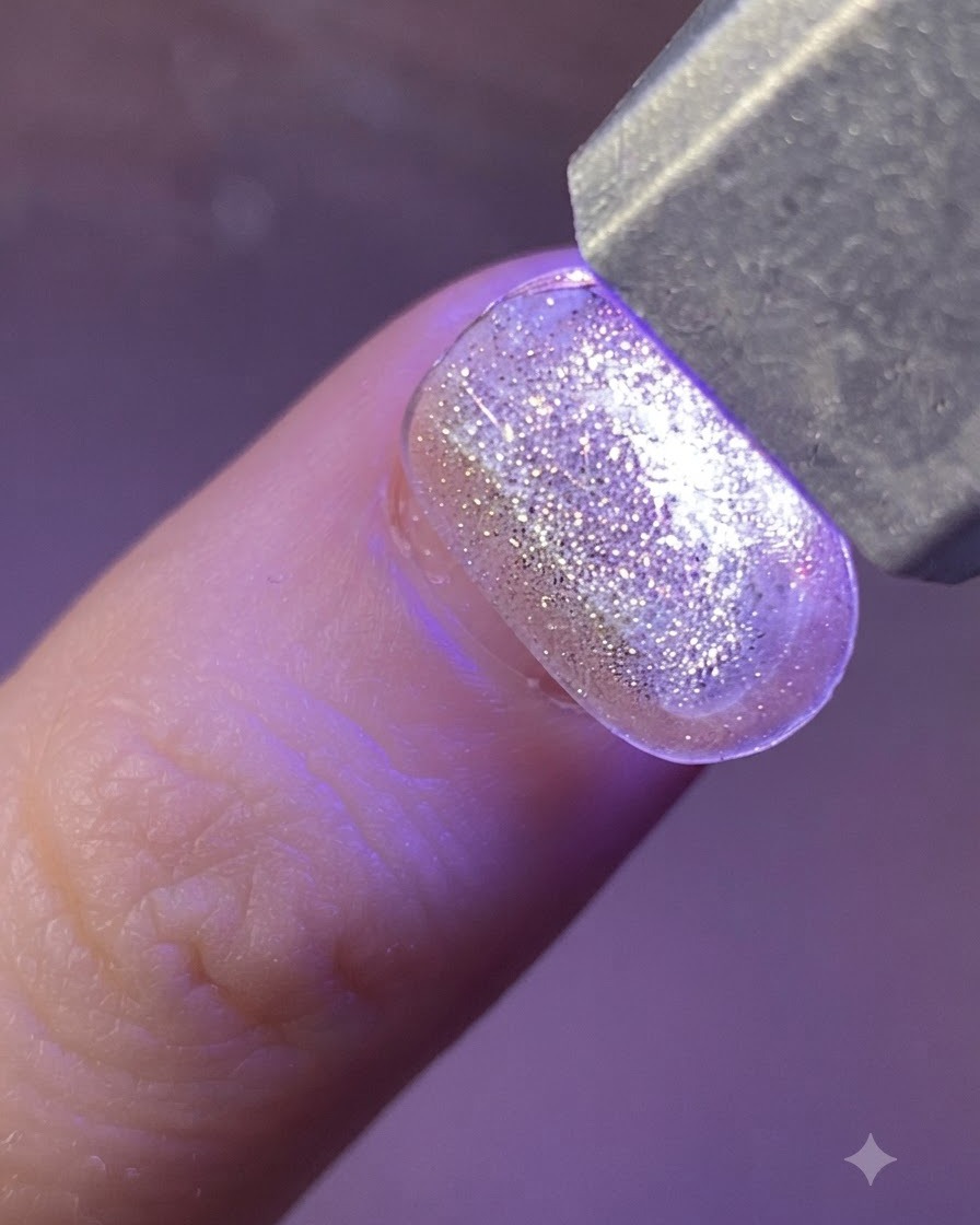 A pair of metal tweezers lifting a holographic star sticker from a clear sheet.