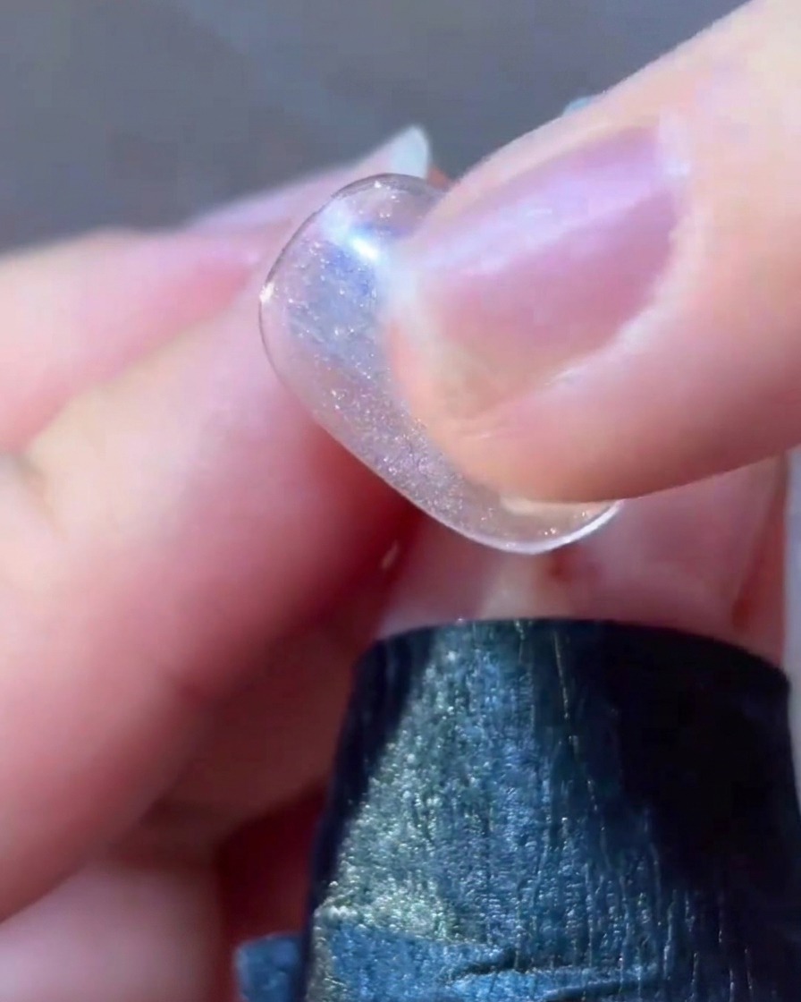 A fine liner brush applying pink gel detail around a star design on a nail.