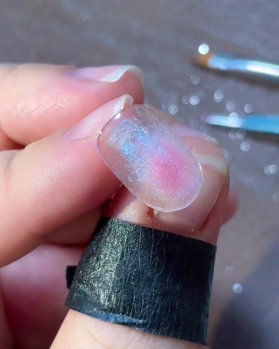 A detailed view of small colorful dots and flakes arranged delicately around a silver star nail art design.