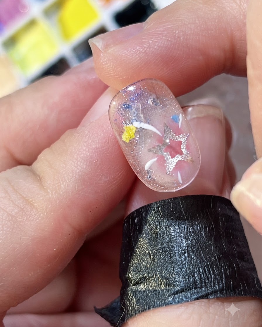 A close-up view of hand-painted white and yellow lines radiating like fireworks on a decorated nail.