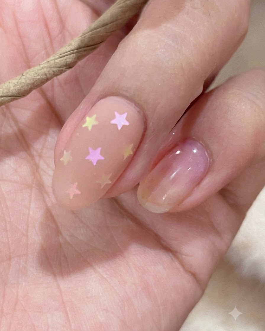 A close-up of a swatch stick displaying nude and pink gel polish shades.