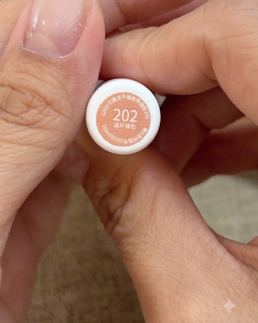 A close-up view of hands holding bottle number 202 honey peach pink gel polish.
