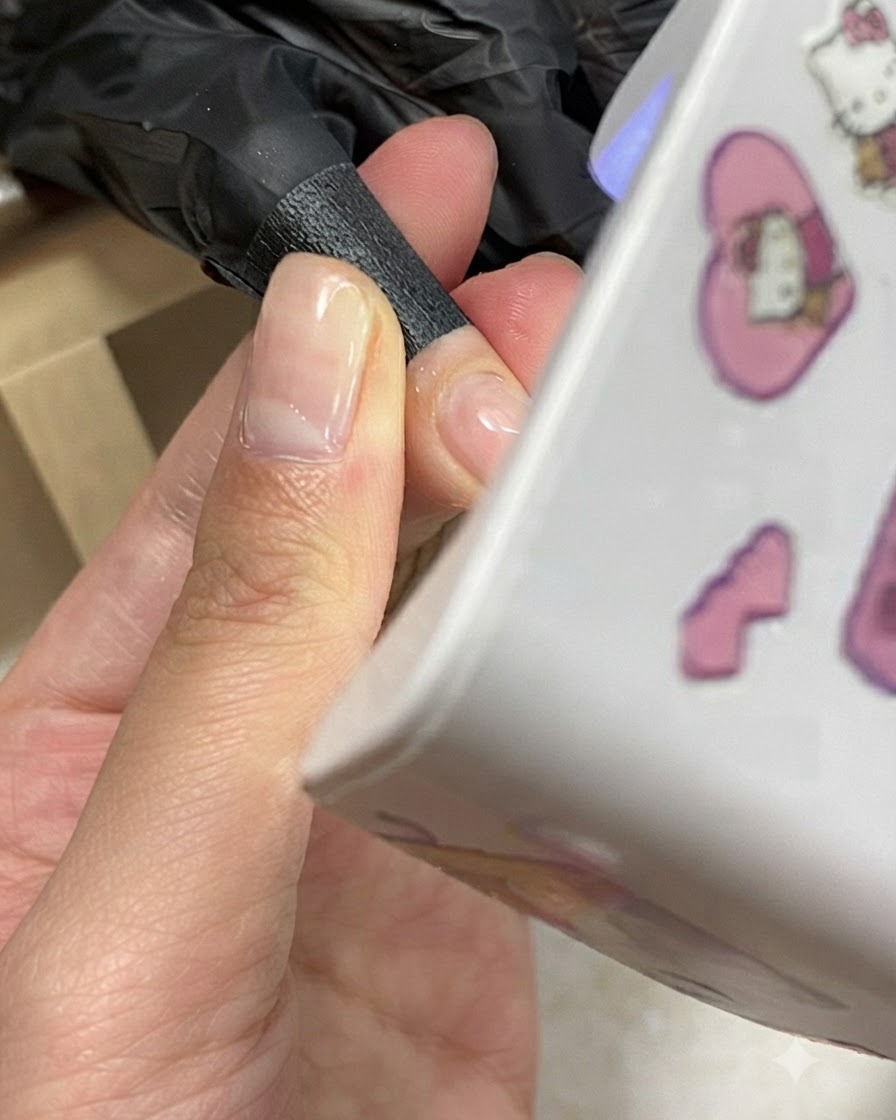 A hand positioned underneath a compact mini UV/LED nail lamp during a gel curing process.