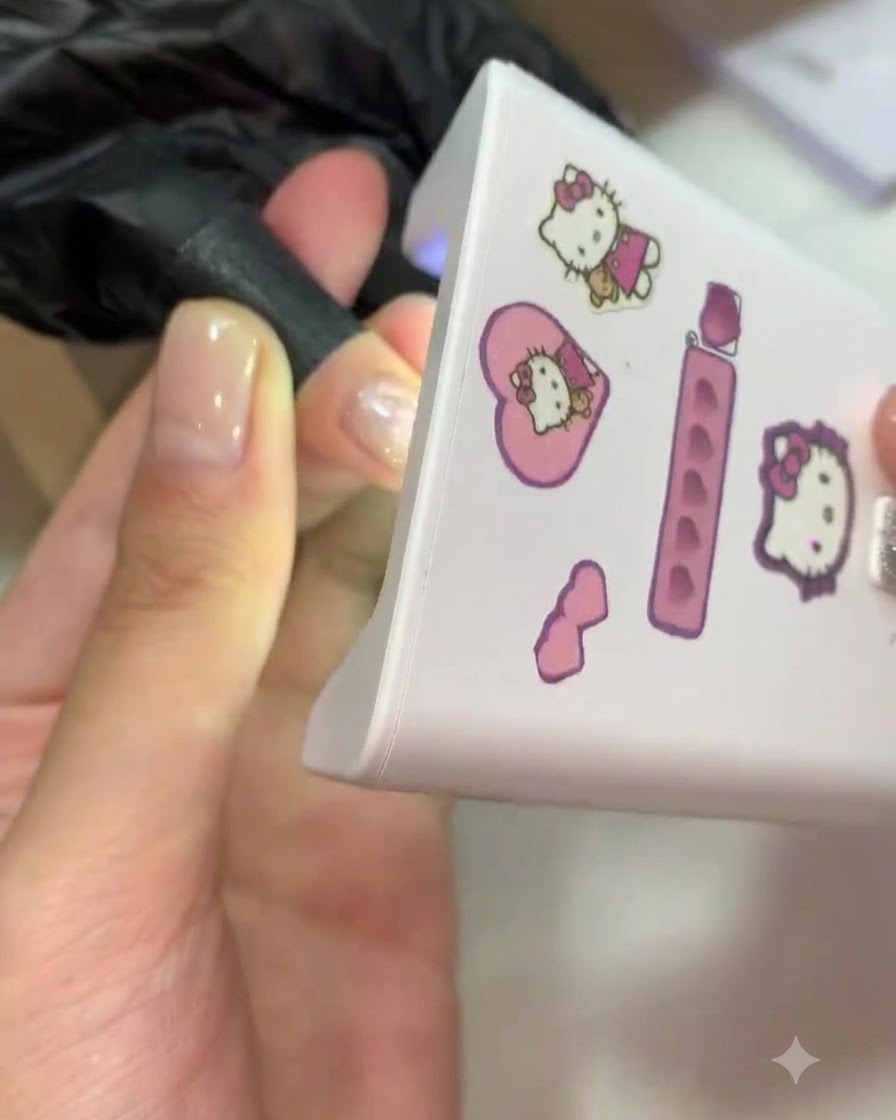 A finger placed inside a mini pink UV/LED lamp for curing.