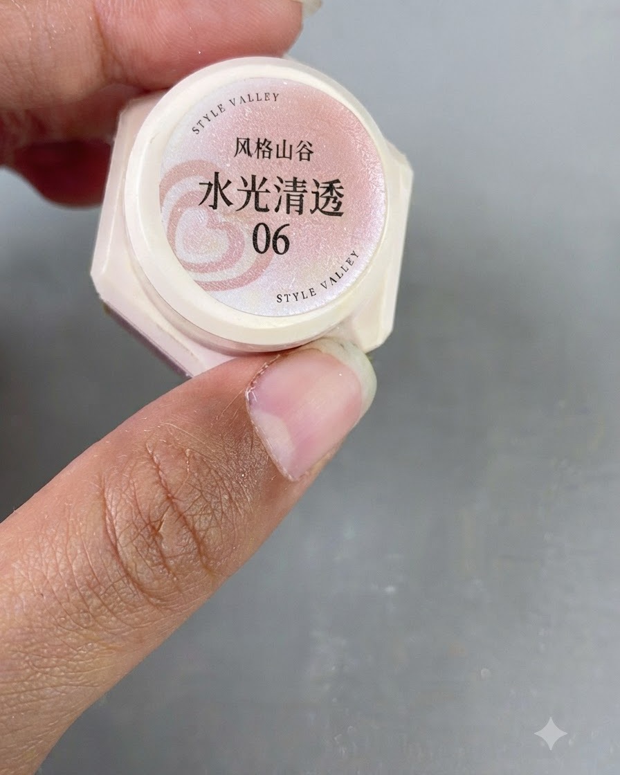 A close-up of a hand holding a small jar of pink translucent cat-eye gel labeled number 06.