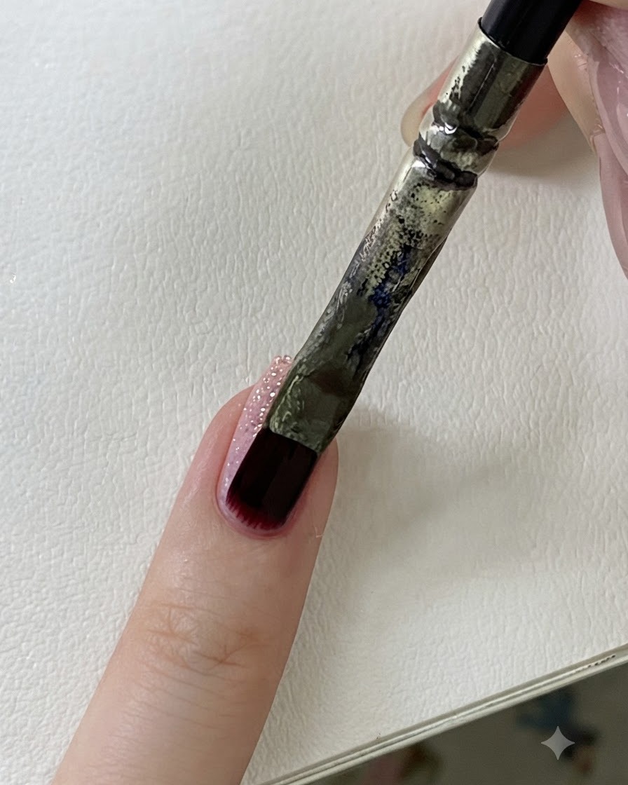 A close-up view showing the side profile of a fingernail highlighting the textured glitter surface.