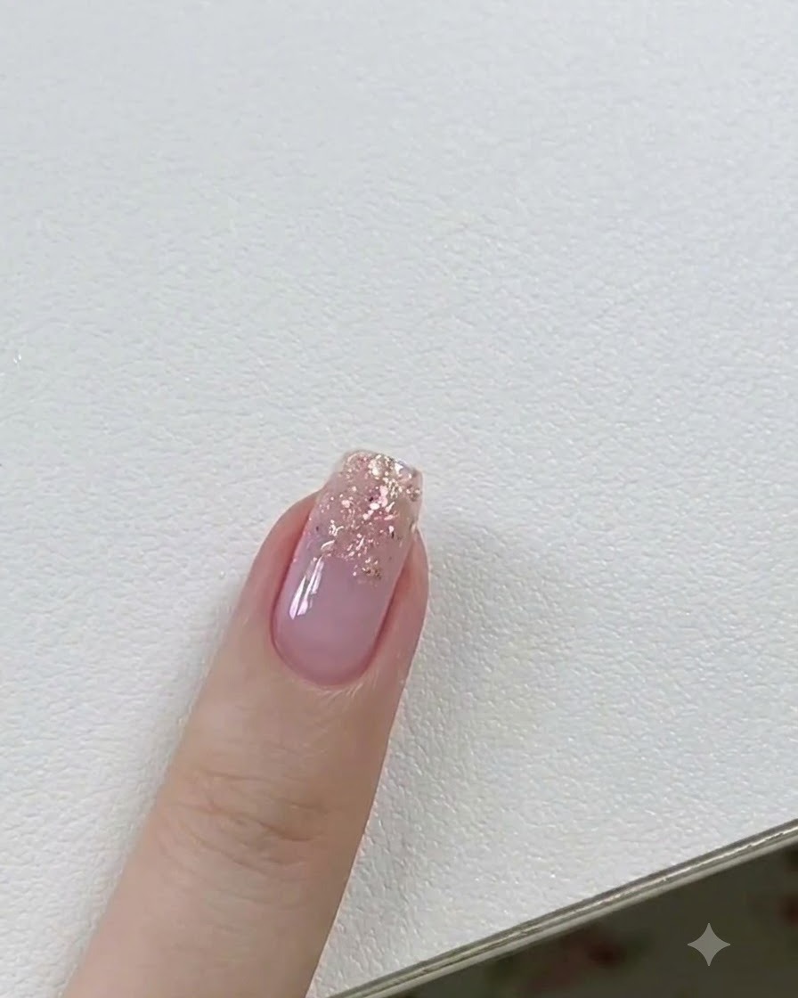 A gel brush applying a thin layer of clear builder gel onto a glitter-accented fingernail.