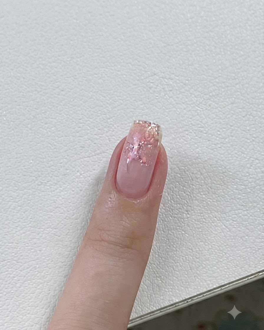 A close-up of a fingernail being cured under a UV/LED lamp with pink gel and star details.