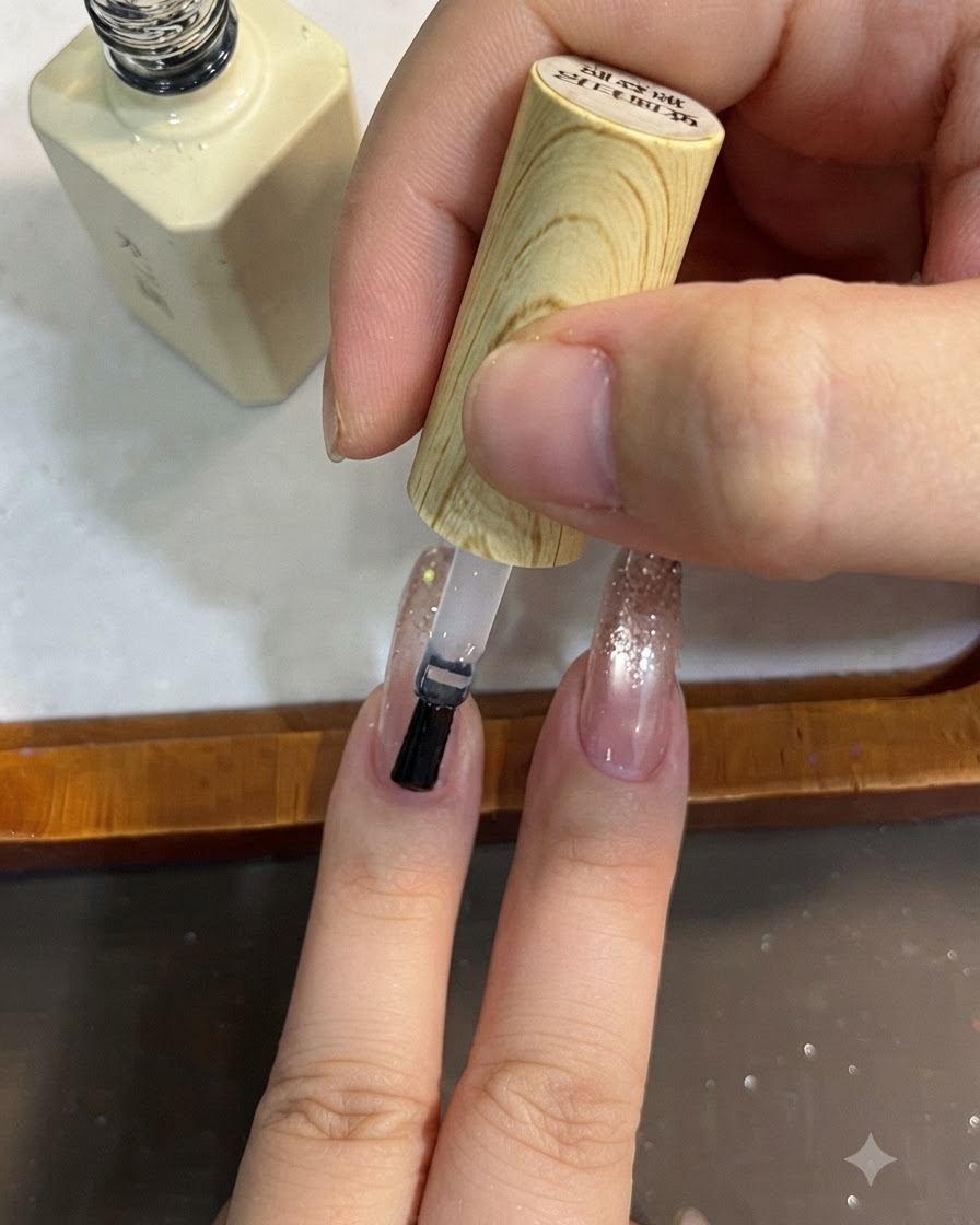 A brush applying clear top coat over a glitter gradient nail design.