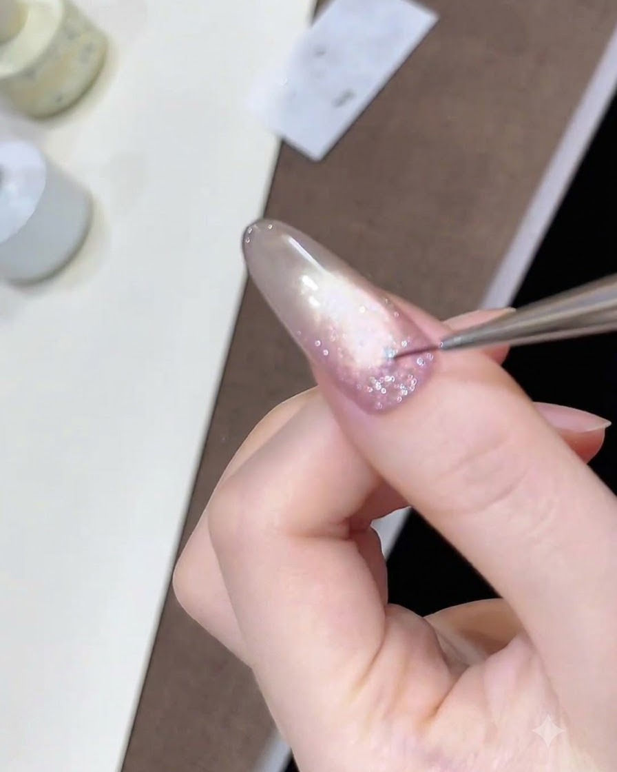 A fine detail liner brush placing tiny star sequins onto the wet glitter gel layer.