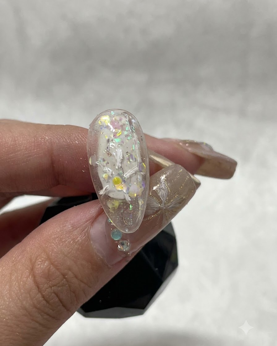 A close-up view of a nail showing the initial white plaster gel strokes forming the start of a floral design.