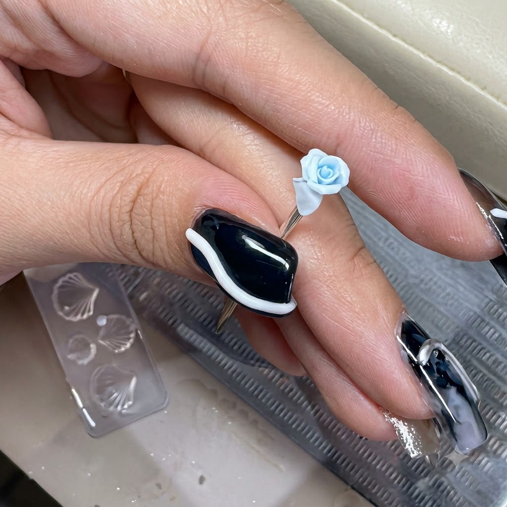 A tiny light blue clay petal being placed onto the outer edge of a miniature sculpted rose.