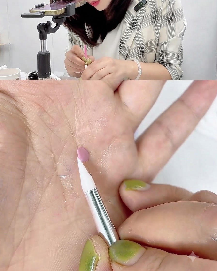 A white silicone carving pen touching and rolling the edge of a small pink gel disc resting on a palm.