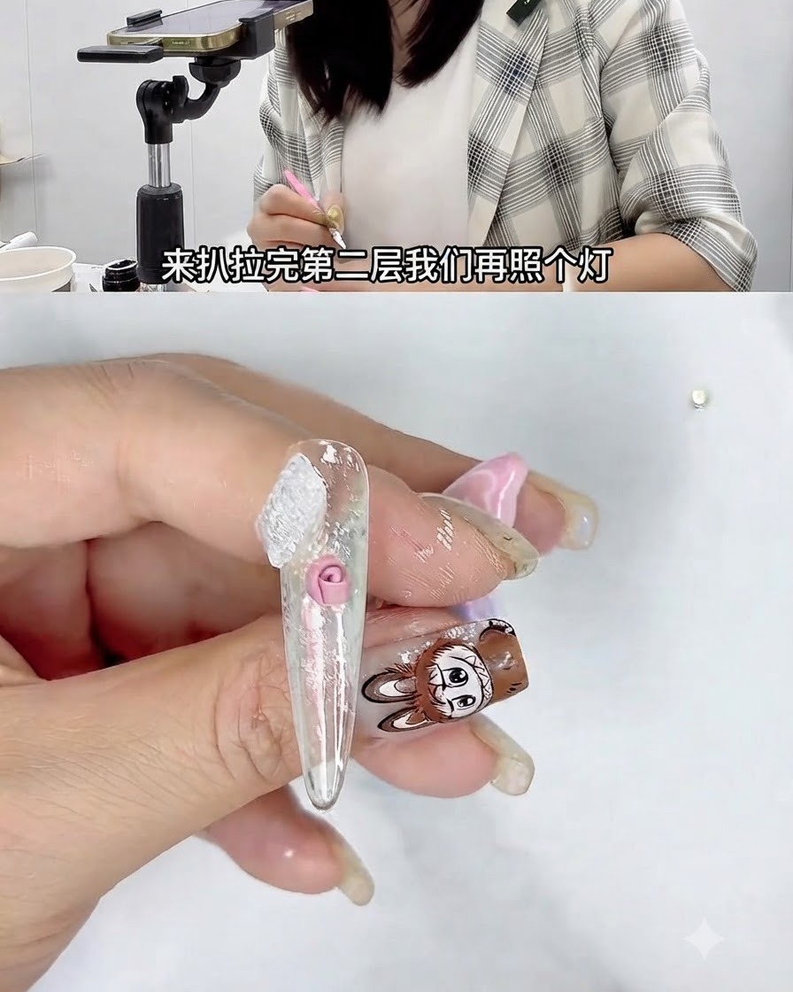 A hand holding a nail under a small UV curing lamp during a 3D nail art tutorial.
