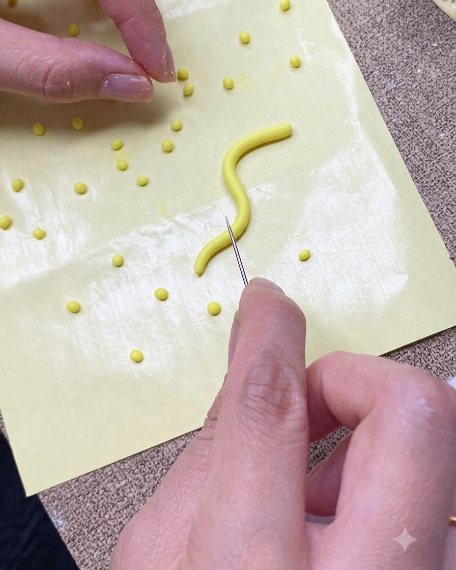 A close-up of hands cutting a yellow gel strip into small portions on a yellow silicone mat using a needle tool.