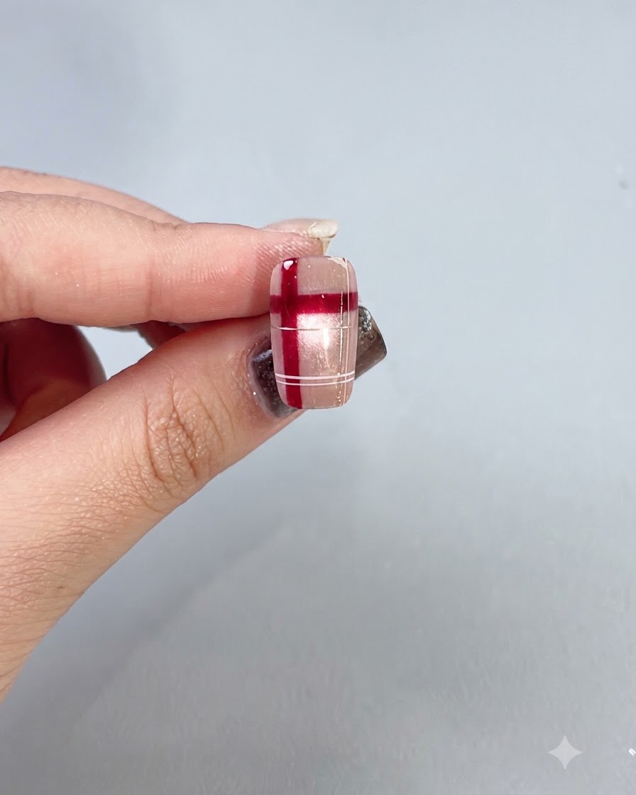 A finished plaid nail design held against a light background, showing a glossy, sealed surface.