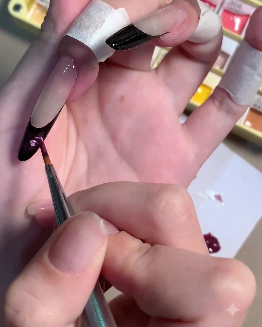 A brush mixing white gel into a dark plum pigment puddle on a palette.