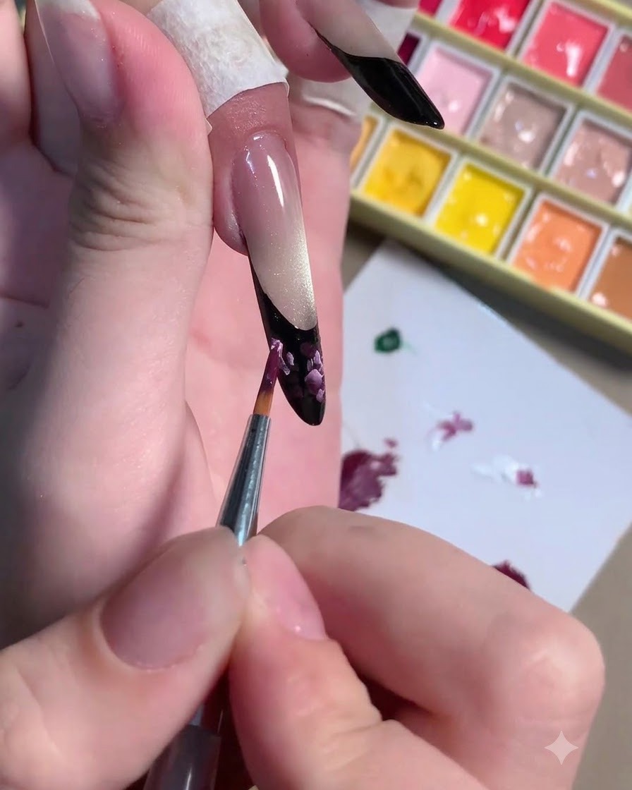 A fine brush applying light pink highlight strokes over the dark plum floral art.