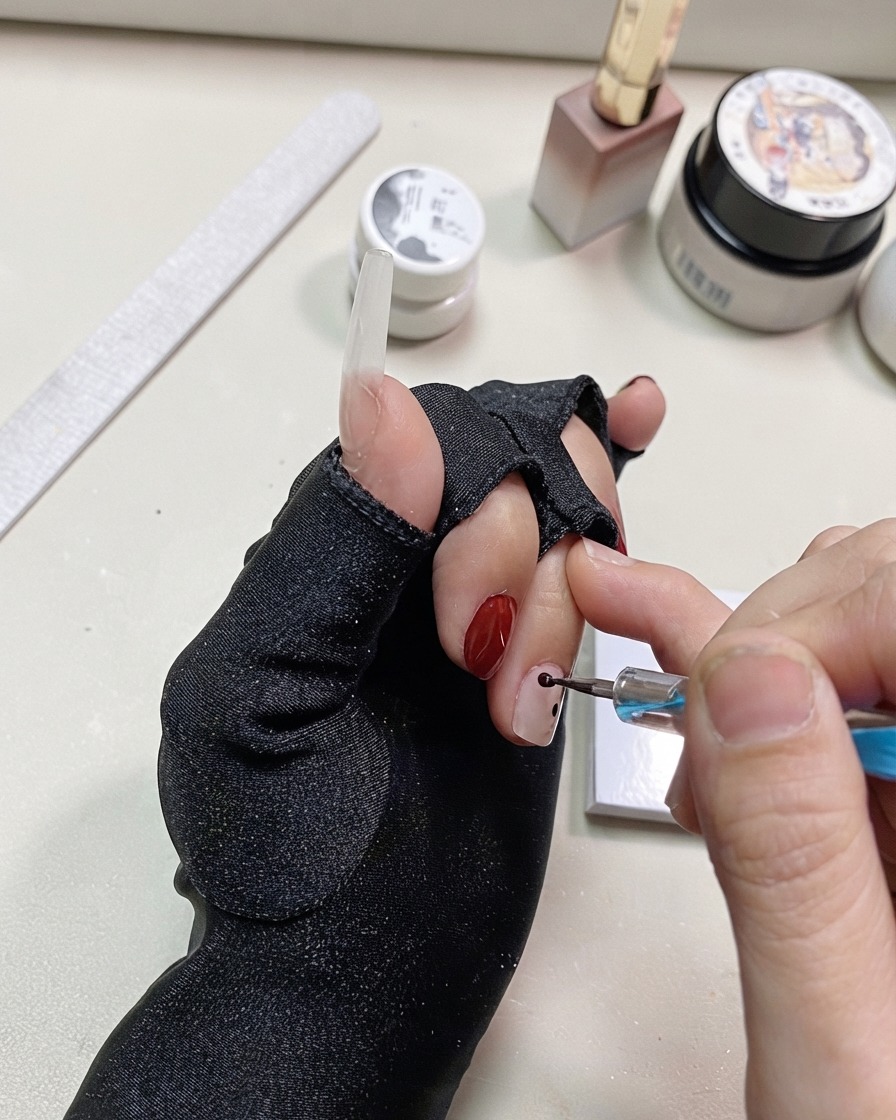 A dotting pen adding more black dots close to the previous points on the nail.
