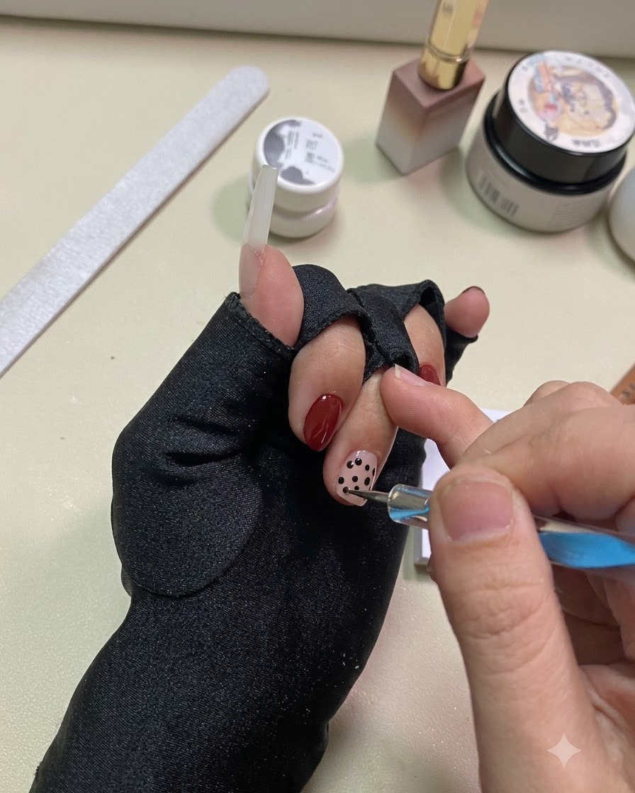 A hand positioned under a UV or LED lamp to cure the black dot details.